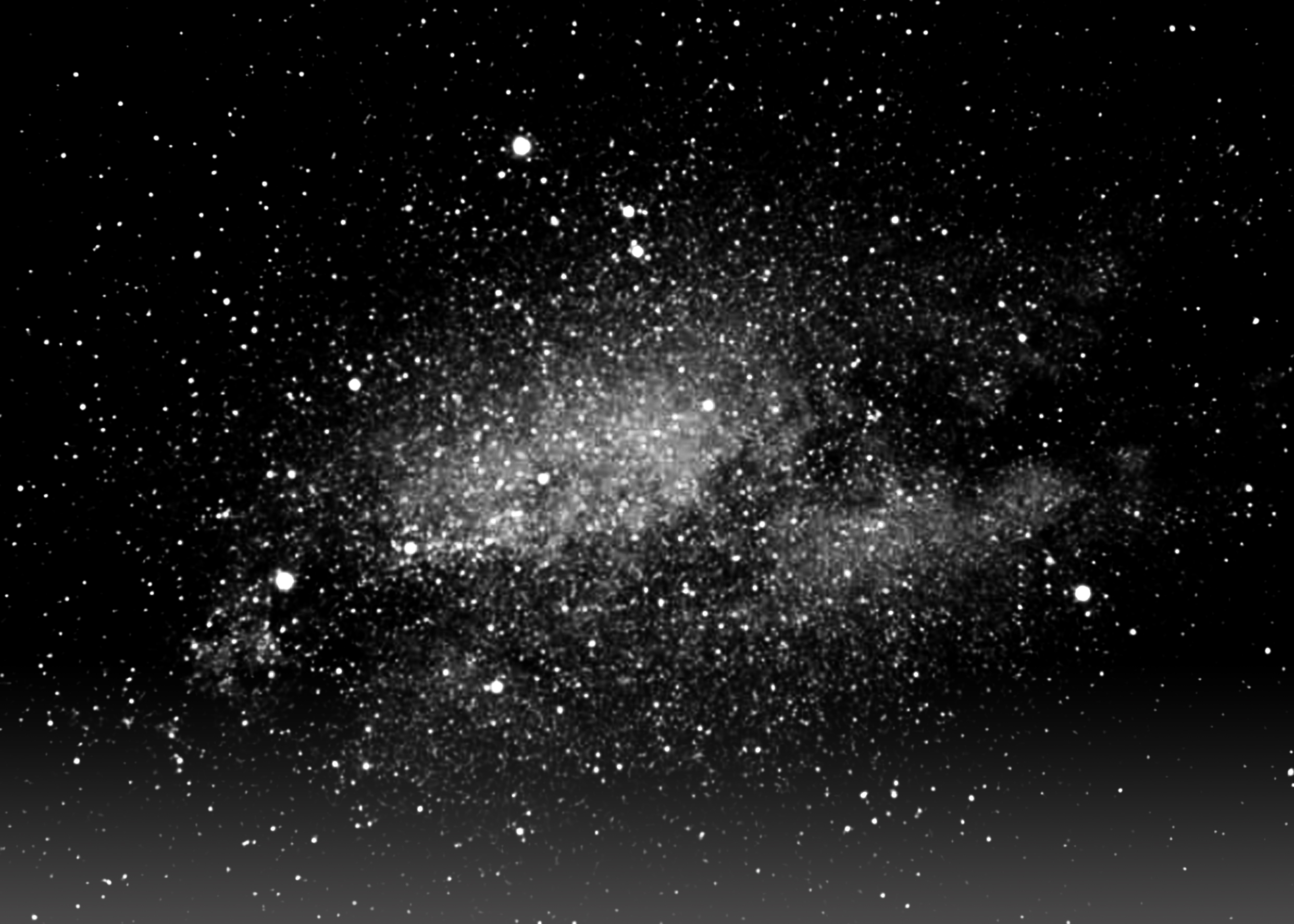 A blurry, relatively low-quality black and white film photo of the Milky Way Galaxy.